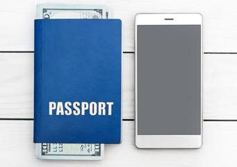 Passport with money and smartphone on white wooden table. Top view.