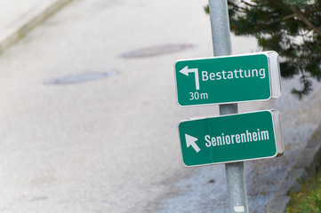 Hinweisschilder weisen den Weg zum Bestatter und zum Seniorenheim