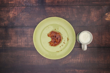 Bread with jam on green plate and cup of milk for breakfast
