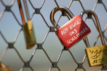 Rotes Vorhängeschloss mit Liebesbotschaft an einen Metallzaun geschlossen