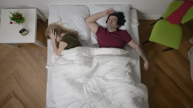 Young irritated woman lying in bed with snoring husband