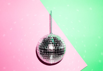 Shiny disco ball on a bright pastel creative background. Pop disco music style attributes eighties