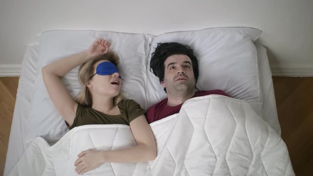 Man is trying to fall asleep while woman is snoring