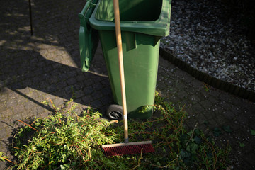 Green wheelie bin / garden waste container and broom filled with fruit and vegetable waste, garden...
