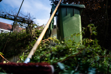 Green wheelie bin / garden waste container and broom filled with fruit and vegetable waste, garden...