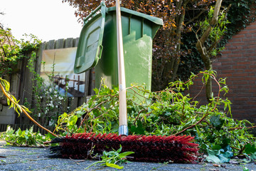 Green wheelie bin / garden waste container and broom filled with fruit and vegetable waste, garden...