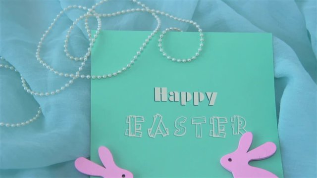 Easter holiday concept with cute handmade card and pink rabbits on turquoise background