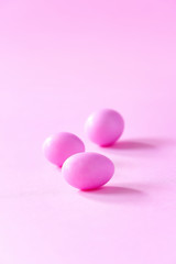Three small pink candy eggs on pink background. Easter celebrate concept. Copy space.