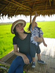 The woman is sitting relax with her nephew at the edge of the rice field.