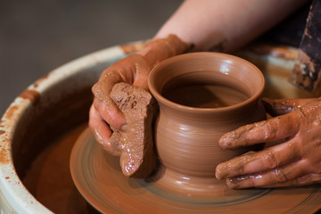 Rotating potter's wheel and clay ware on it taken from above. A sculpts his hands with a clay cup on a potter's wheel. Hands in clay. 