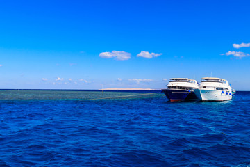 Fototapeta na wymiar White yachts anchored near coral reef in Red sea, Egypt