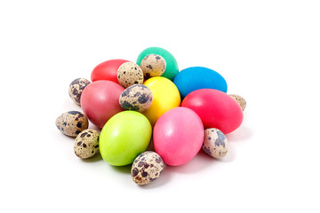 Colored Easter eggs lie on a white background. Yellow, red, green, blue eggs and quail eggs folded together in a pile