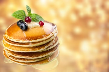Stack of Small pancakes in syrup on background