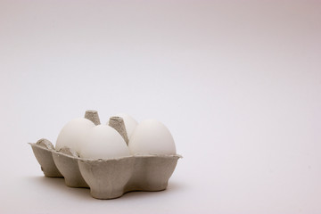 White chicken eggs in egg carton box close up on white background