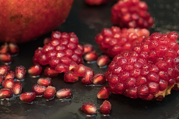 Fresh colorful pomegranates fruits close up on black table	