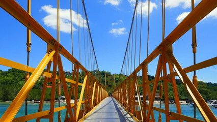zentraler Blick auf gelbe Brücke zwischen den Inseln Lembongan und Ceningan in Indonesien unter blauem Himmel