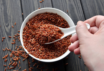 hand holdind a spoon with uncooked red rice