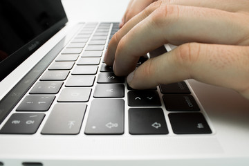 Business person using the keyboard of a laptop on a white table. Person working.