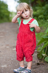 cute two years old blonde white girl in red pants full-size standing on summer outdoor background