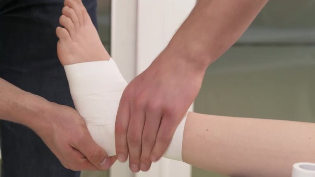 A demonstration video of a professional therapist straddling and massaging taped with sport tape ankle. Tibia joint injury