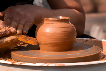 Fototapeta na wymiar Hands of a street potter make a clay pot on a potter's wheel. Close-up