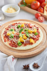 Raw pizza with ingredients in the background