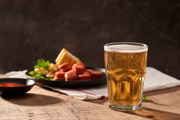 Beer and appetizing beer snacks set. Table with mug beer grilled sausages with sauces.