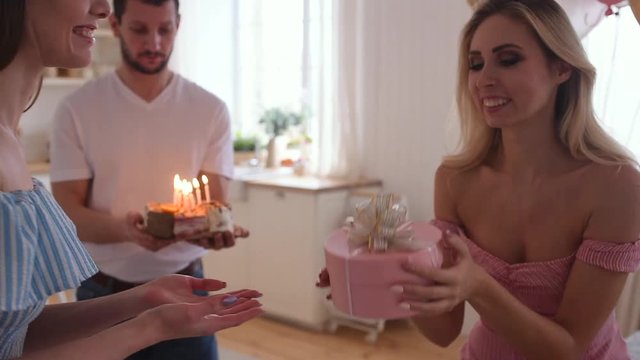 Birthday party of young pretty woman blowing out candles on birthday cake