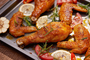 Roasted chicken wings on baking tray over dark wooden background with copy space. Top view, flat lay