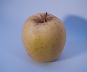 Ripe yellow apple with black spots in white background.