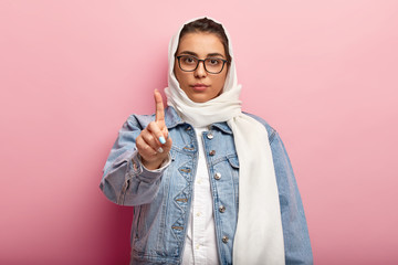 People, religion, ethnicity, body language concept. Serious Islamic woman raises fore finger, warns...