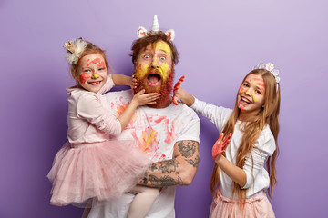 Emotional bearded busy father spends time with two naughty daughters who leave palm prints on his...