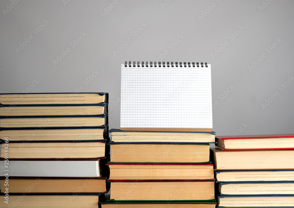 Poster open blank notebook is standing on the stack of books
