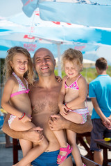 portrait of young happy father with daughters by the sea