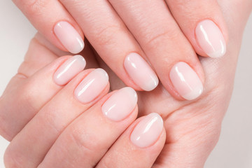 Closeup top view of elegant pastel pink natural manicure. Female hands isolated on white...