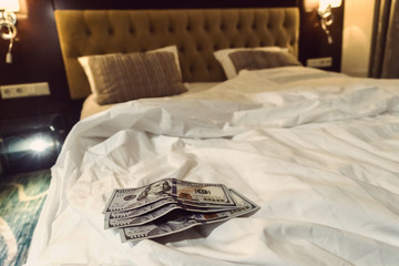 paying money dollar on white bed in hotel