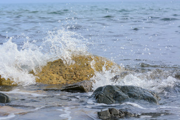 The wave breaks on the rock and forms a lot of spray