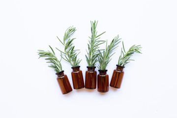 Bottle of essential oil with rosemary on white