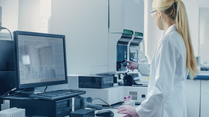 Female Research Scientist Working with Medical Analyzing Machine for Testing Tubes with Blood Sample. Scientist Works in Innovative Pharmaceutical Genetic Research Laboratory.