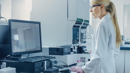 Female Research Scientist Working with Medical Analyzing Machine for Testing Tubes with Blood Sample. Scientist Works in Innovative Pharmaceutical Genetic Research Laboratory.