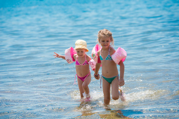 little girls with swimming armbands playing in shallow water