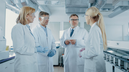 Team of Research Scientists Have Meeting, They Have Discussion While Standing in the Middle of...