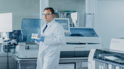 Male Research Scientist Walks Through Laboratory with Tray of Test Tubes Filled with Samples. In...