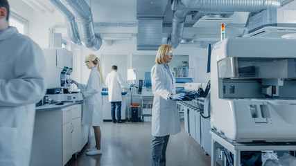 Team of Research Scientists Working On Computer, with Medical Equipment, Analyzing Blood and Genetic Material Samples with Special Machines in the Modern Laboratory. - obrazy, fototapety, plakaty