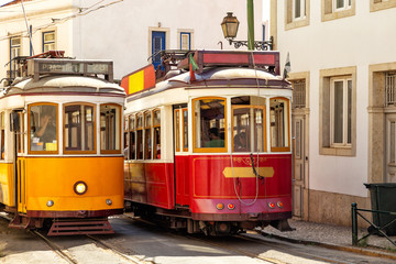 Naklejka na ściany i meble Yellow and red vintage trams on old streets of Lisbon, Alfama, Portugal, popular touristic attraction and destination.