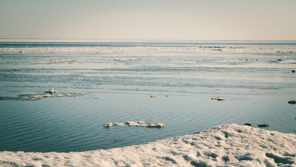 Snow pile, hill. Large snow drift isolated on a blue sky background,  outdoor view of ice blocks at frozen finland lake in winter