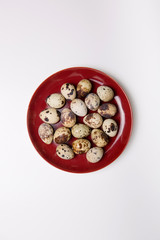 Quail eggs on a red plate on a white background