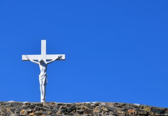 white crucifix with Jesus with blue sky background 