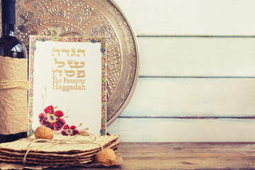 Pack of matzah or matza, Passover Haggadah and red kosher wine on a vintage wood background with copy space.Hebrew text translation: The story of Passover