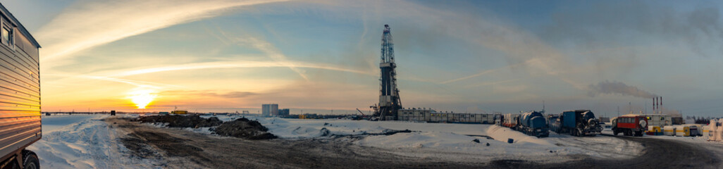 drilling rig on land in winter in the cold against the sunset and the beautiful sky panorama